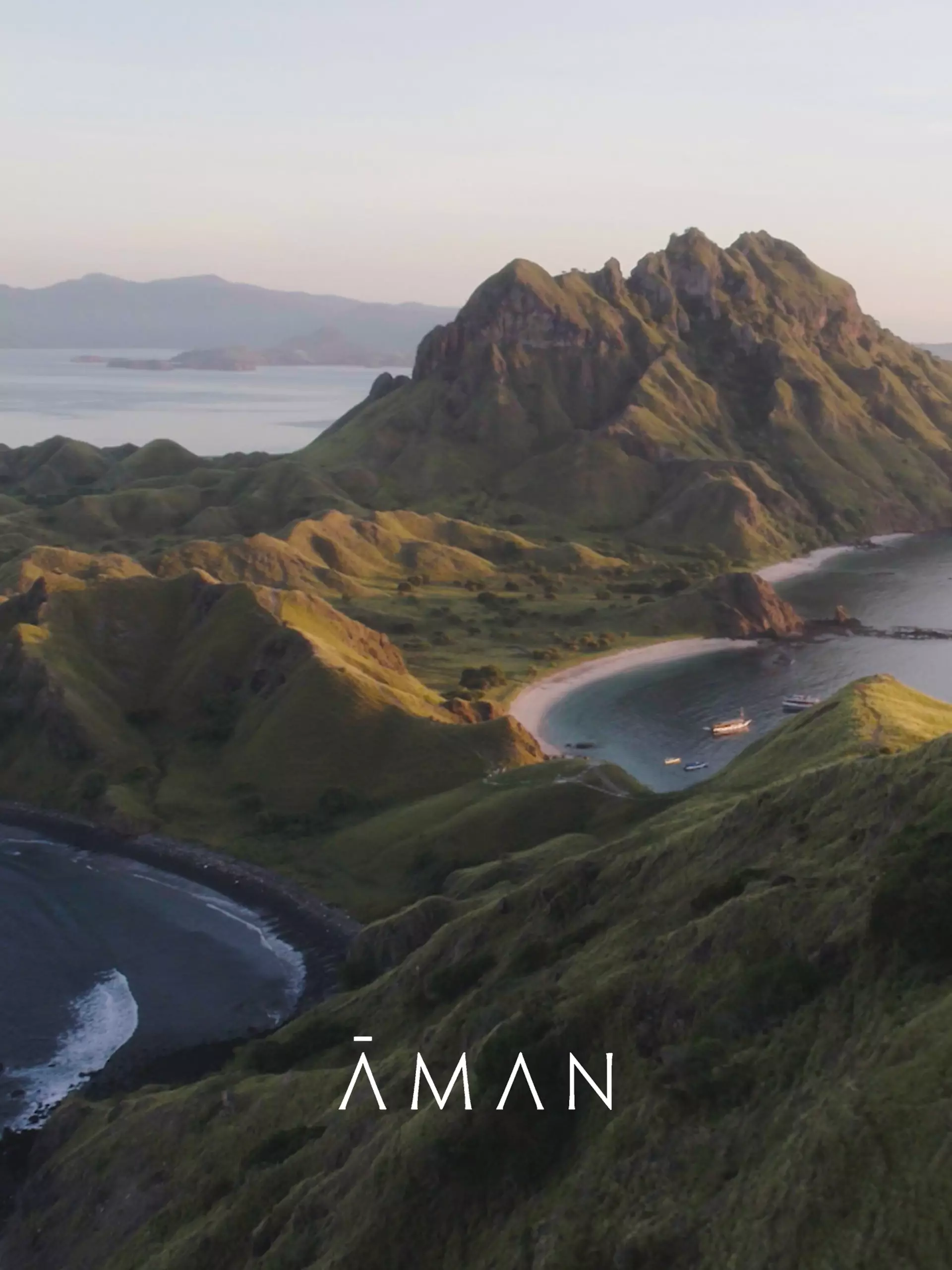 Landschaft mit grünen Hügeln, Buchten und Booten im Wasser, Logo Aman für exklusives Reisebüro in Hamburg