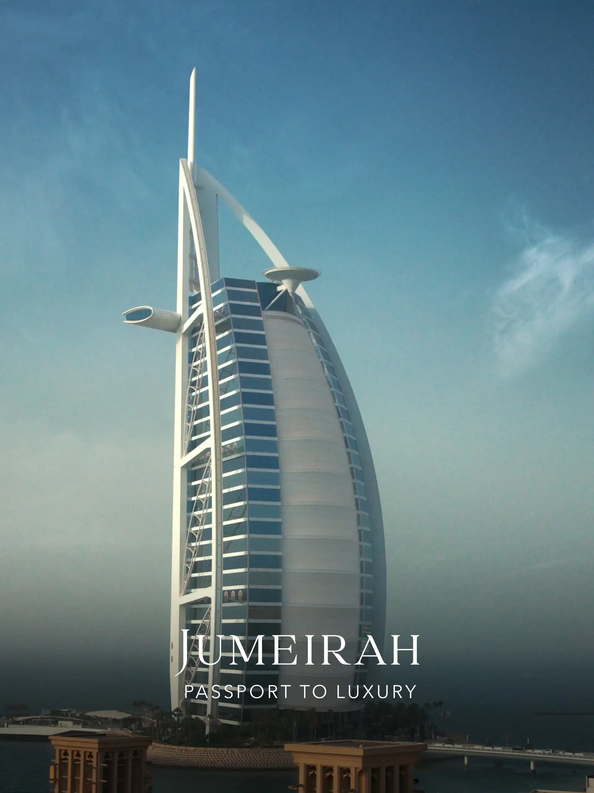 Das luxuriöse Jumeirah Hotel in Dubai vor klarem Himmel mit Schriftzug Passport to Luxury für Reisebüro Hamburg.